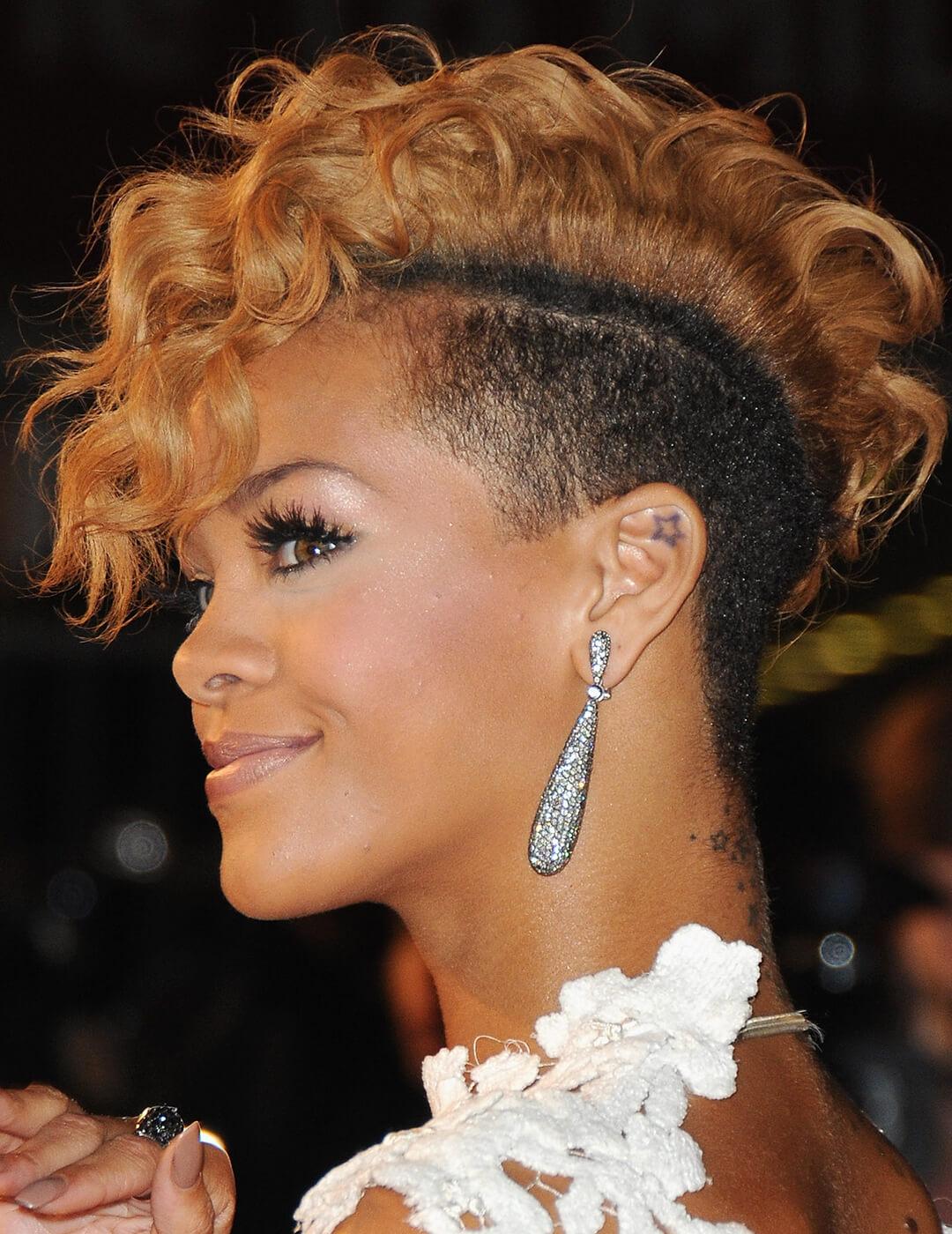 Rihanna sporting a two-toned undercut hairstyle, neutral makeup look, silver dangling earrings, and white floral dress at the red carpet Mobile