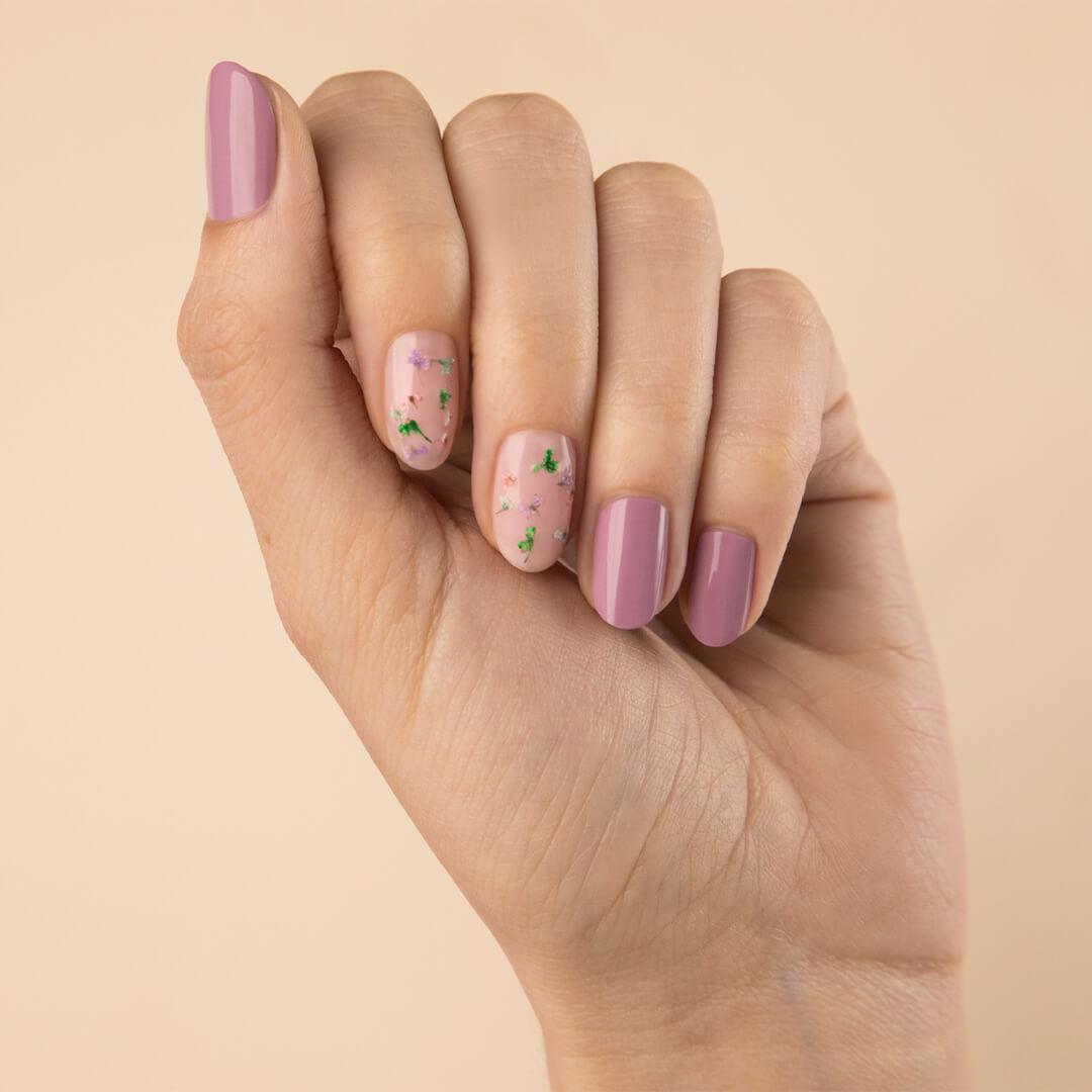 Close-up of a model's hand with mauve nail mani and dried flowers accent nail art Mobile