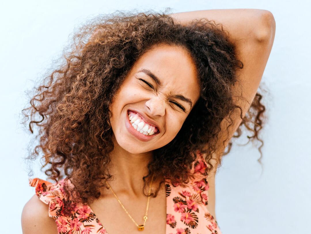 Image of a young woman with curly hair smiling big and posing Desktop