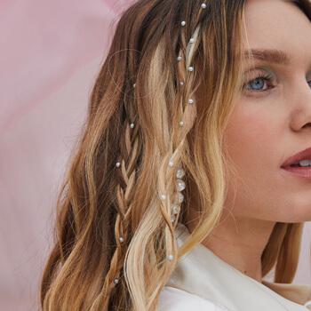 A close-up image of a blue-eyed model showing her pearl studded loose braids Mobile