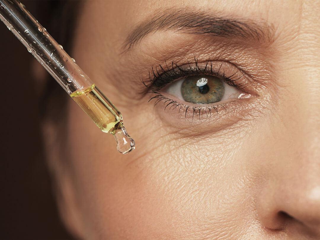 An image capturing the close-up detail of an elderly woman's eye with an eyedrop serum dropper Desktop