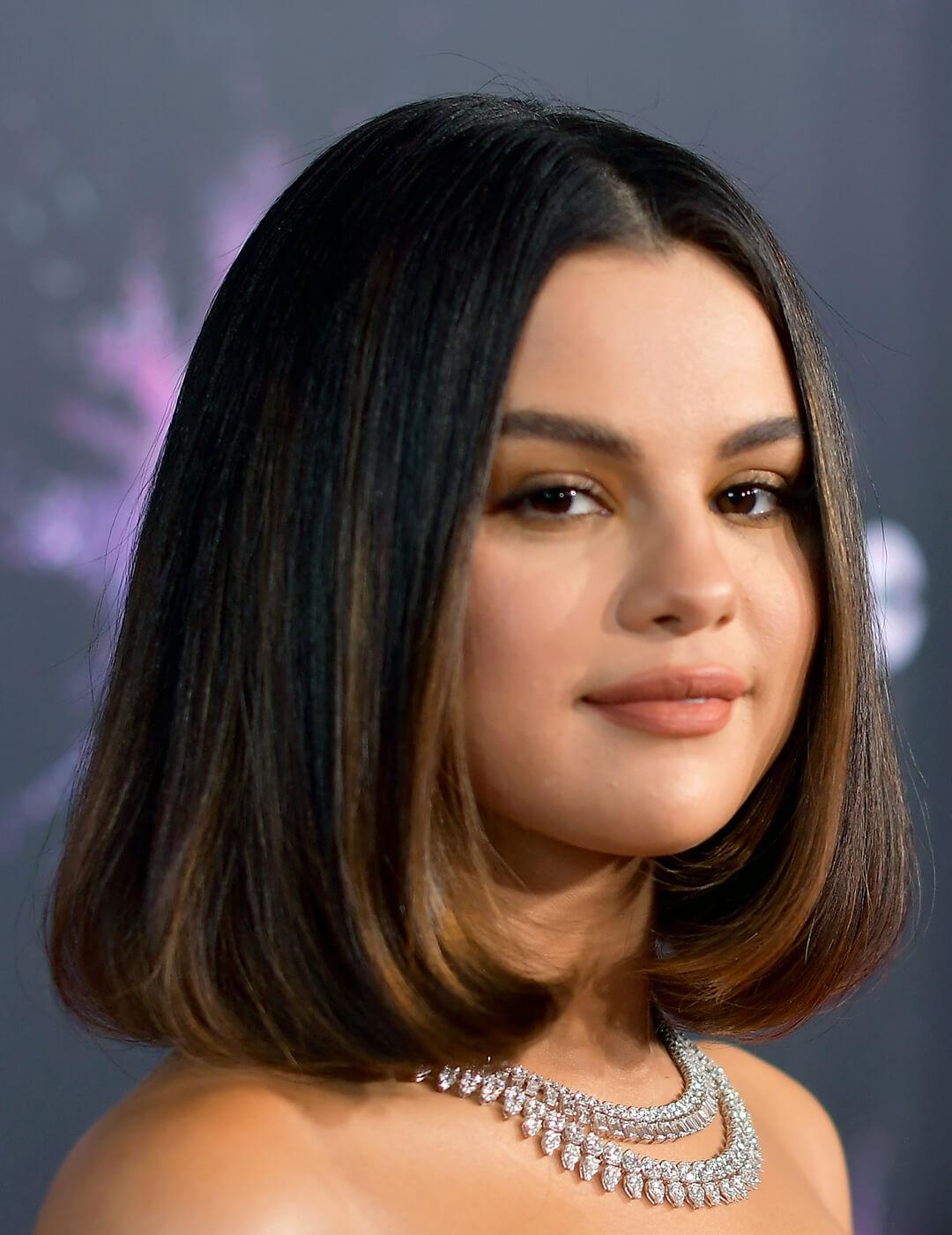 A photo of Selena Gomez appearing in her dark-colored hair paired with an elegant silver necklace Mobile