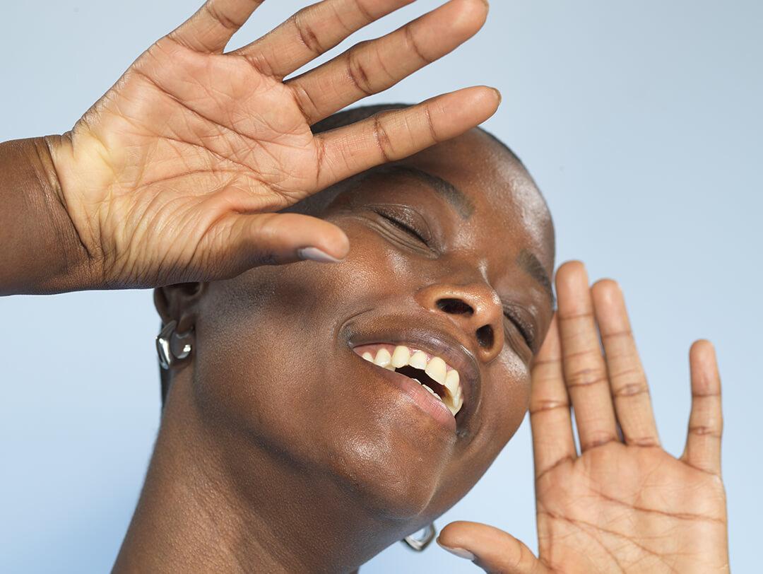 A photo of a model smiling and gesturing with hands on a blue background Desktop
