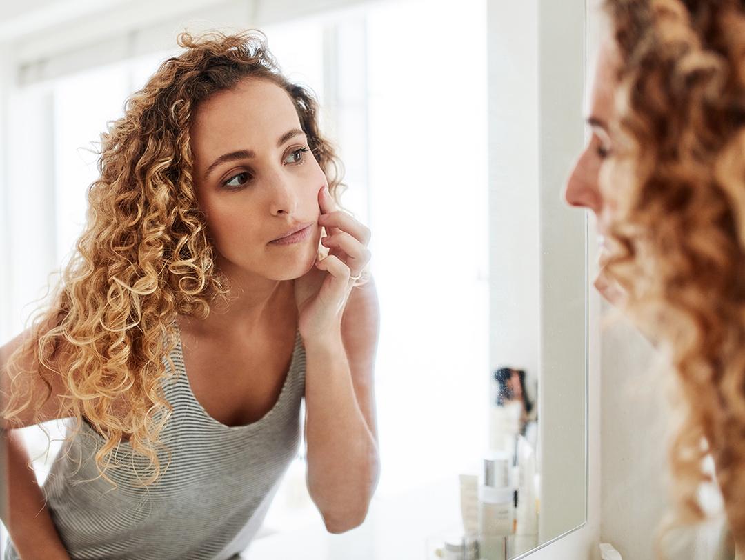 Image of a woman checking her face in the mirror Desktop