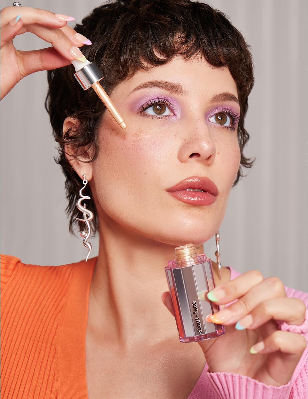 Halsey applying ABOUT-FACE Light Lock Highlight Fluid on her cheek with a dropper Mobile