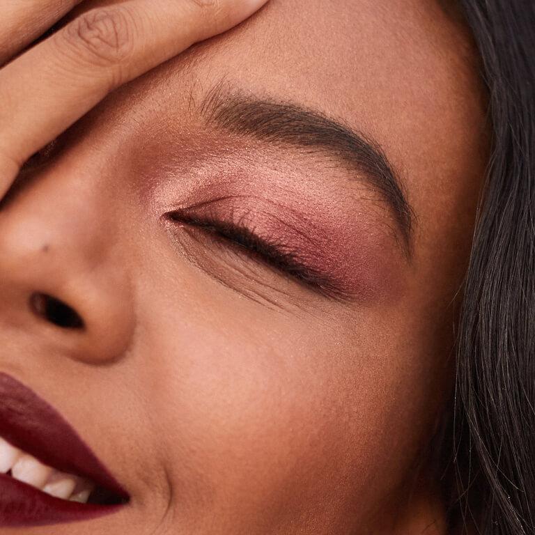 An image of a model rocking a rose gold eyeshadow look covering half of her face with her hand Mobile