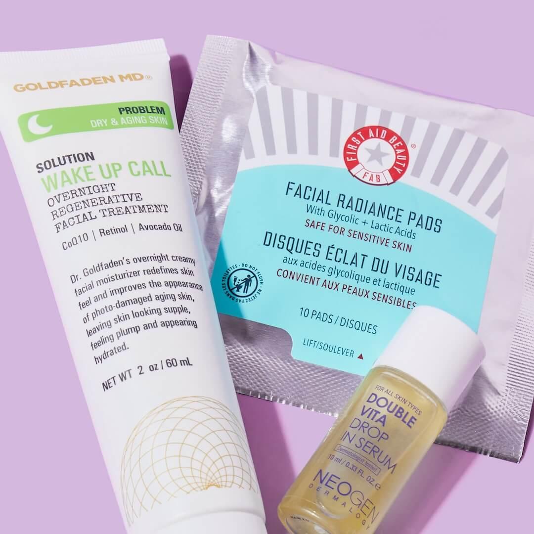 A closeup of different skincare products from various brands on a purple background Desktop