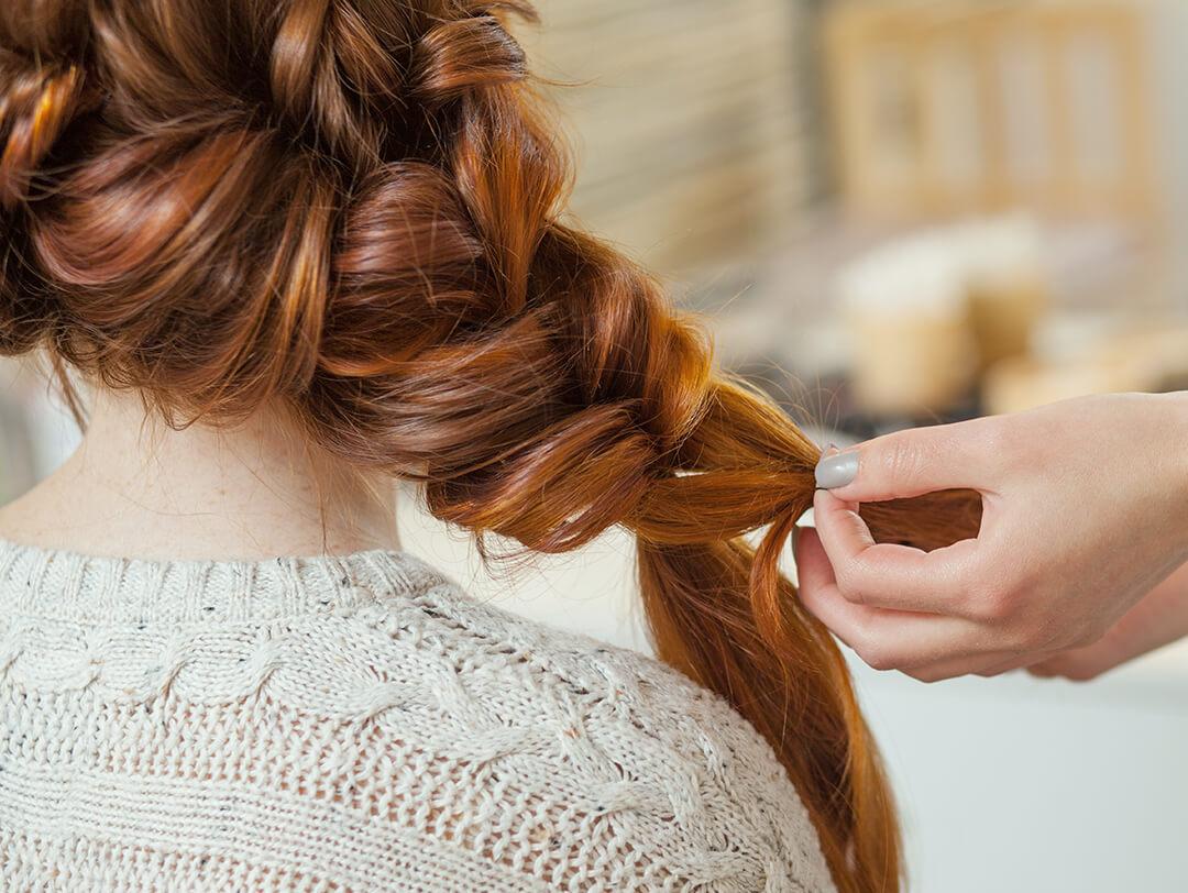Hairstylist braiding a woman's red hair Desktop
