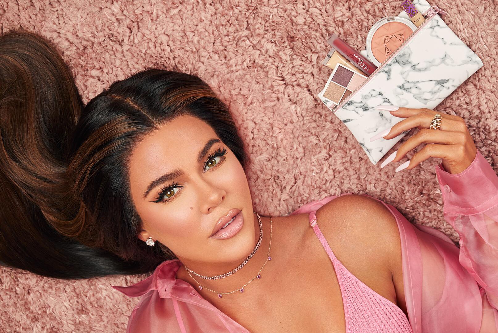 Khloé Kardashian holding an IPSY January 2020 Glam Bag while lying on pink carpet Desktop
