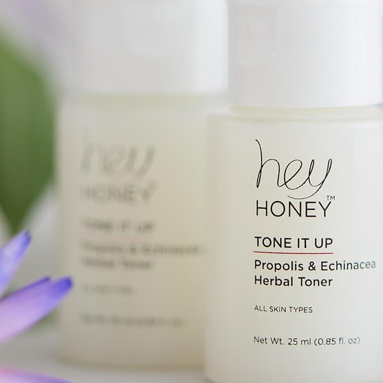 A close-up image of HEY HONEY Tone It Up! Propolis & Echinacea Herbal Toners and a purple flower Mobile