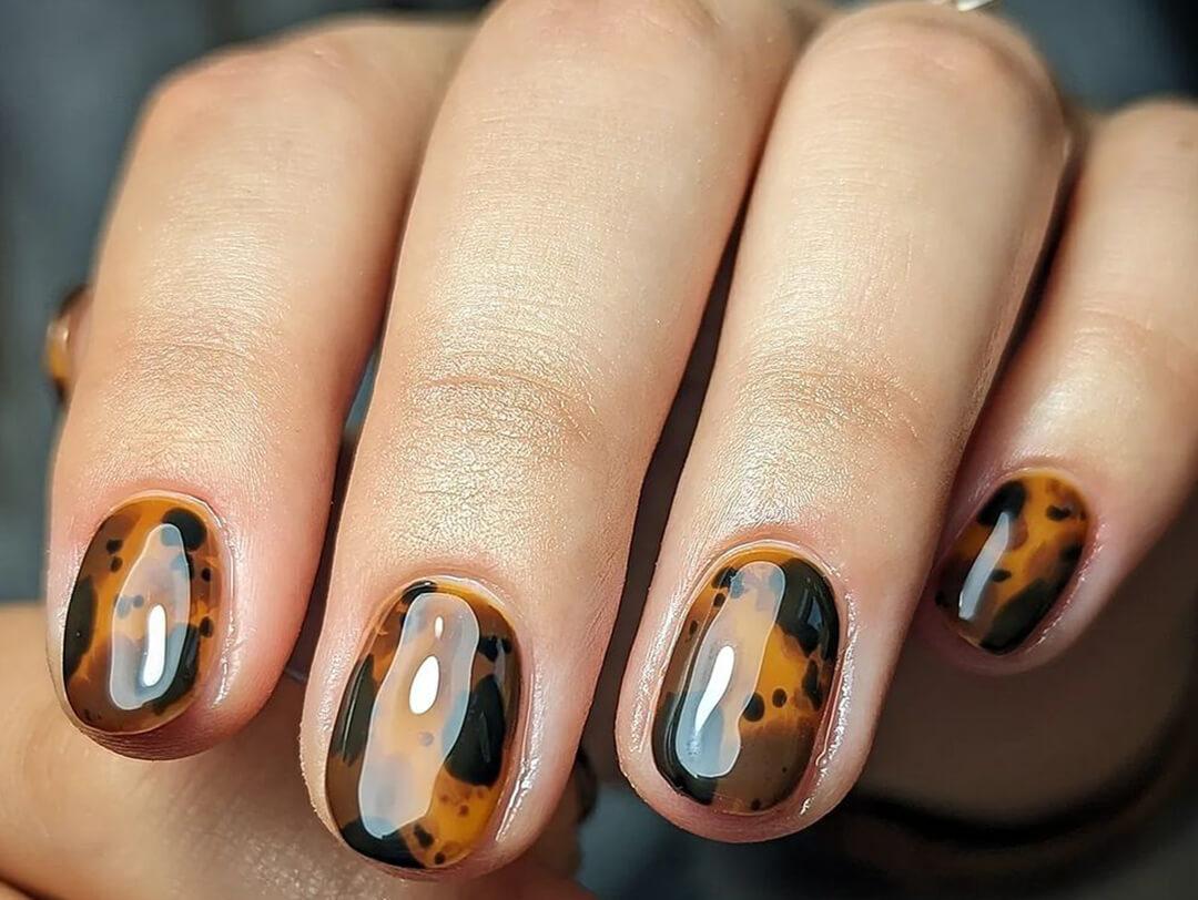 Close-up of a woman's hand with glossy, tortoise shell design nail art Desktop