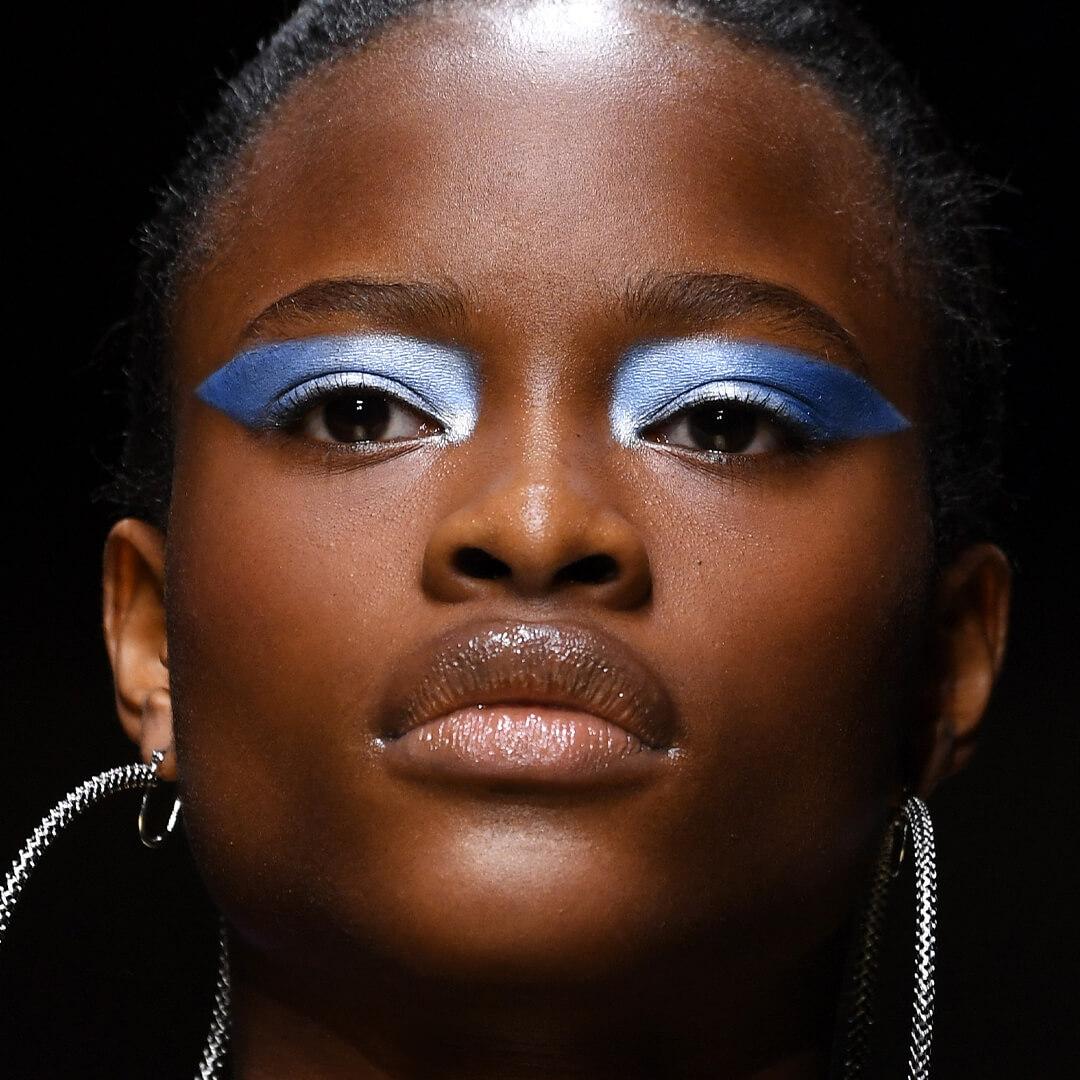 Close-up image of a black female model rocking a geometric shimmery blue eyeshadow look Mobile