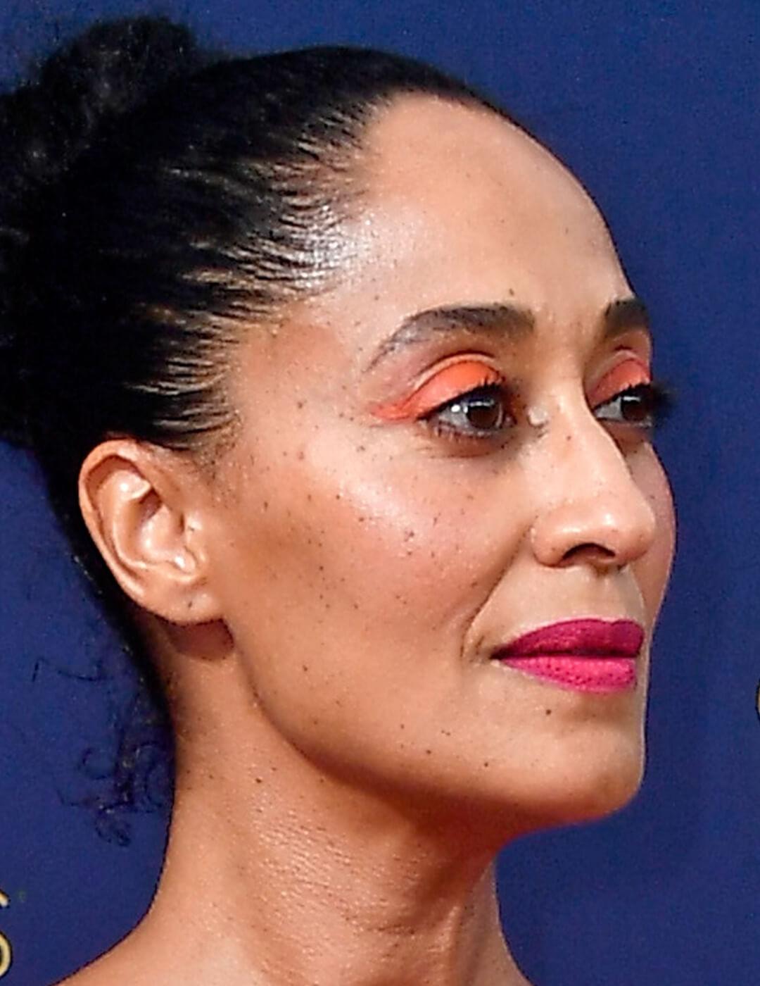 A photo of Tracee Ellis Ross with a neon orange eyeshadow and bold red lipstick Mobile