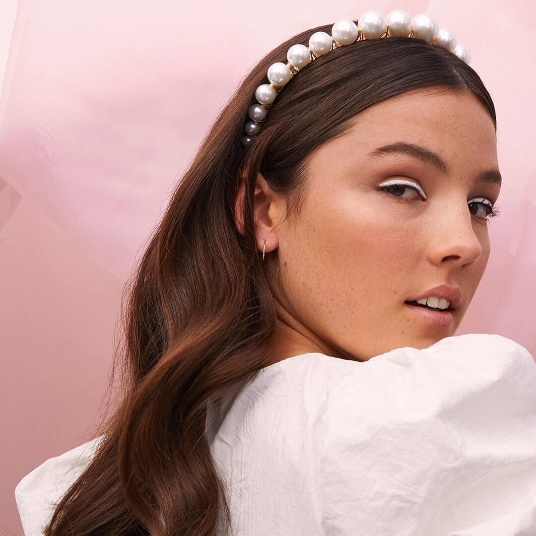 Close-up image of a model rocking a white eyeliner look and pearl-studded headband Desktop