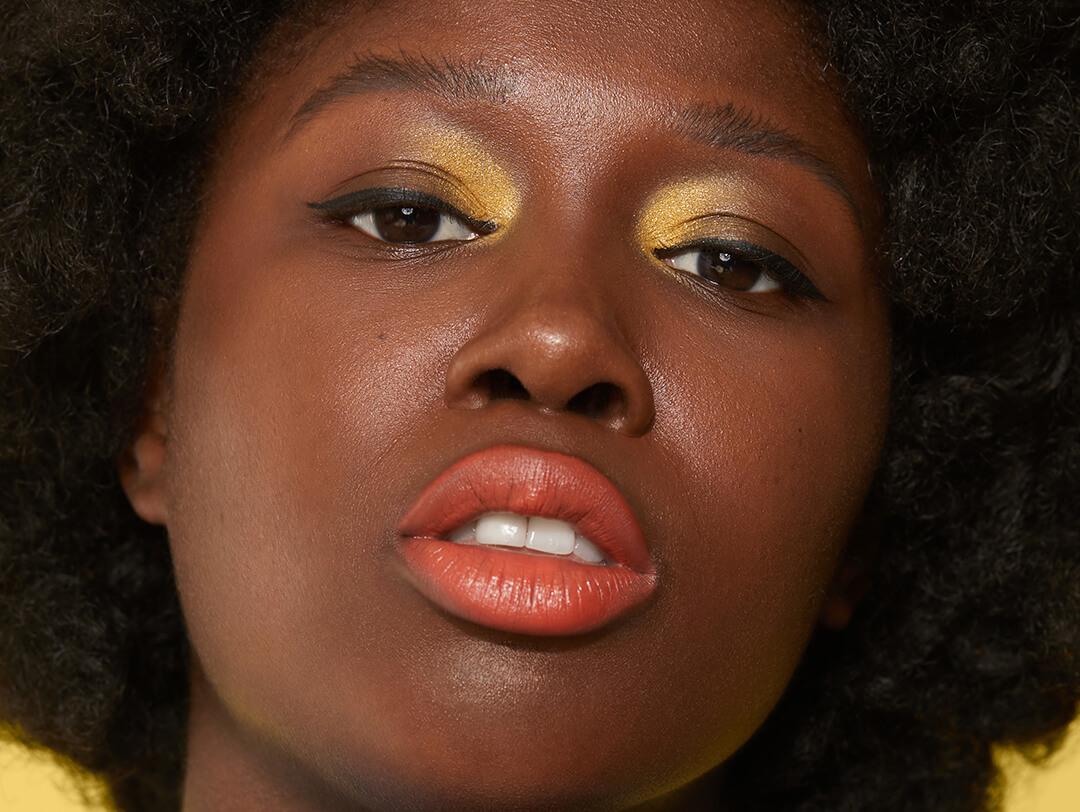 Close-up of a Black female model rocking gold eyeshadow and orange lipstick Desktop