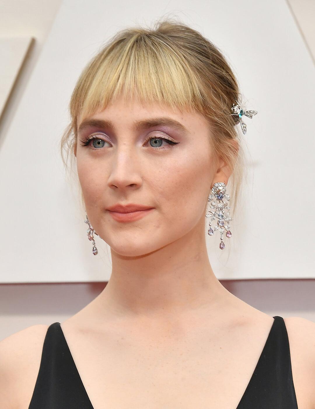 Saoirse Ronan looking elegant in silver jewelry, black dress, lavender eyeshadow makeup look, and updo hairstyle with bangs Mobile