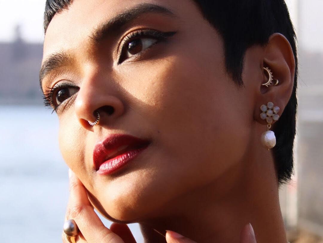 Close up image of Tanwi Nandini Islam rocking a pixie-cut hairstyle and dangling pearl earrings and posing Desktop