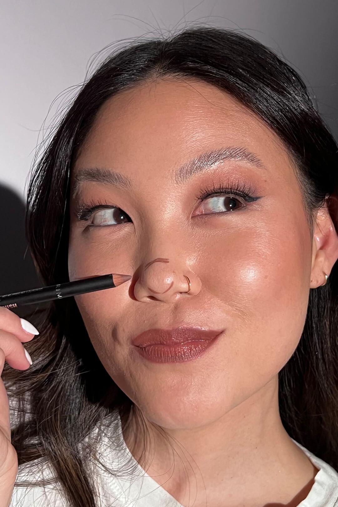 A closeup of a model's face with a glowy look, mauve lipstick, and contour on the nose Desktop