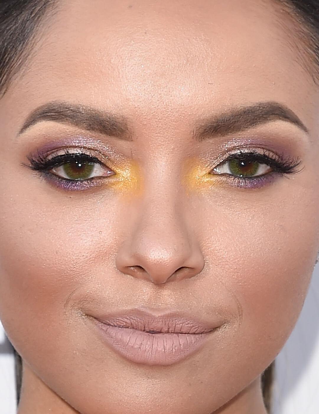 Close-up image of Kat Graham rocking a purple and yellow eye makeup look paired with a nude lip Mobile