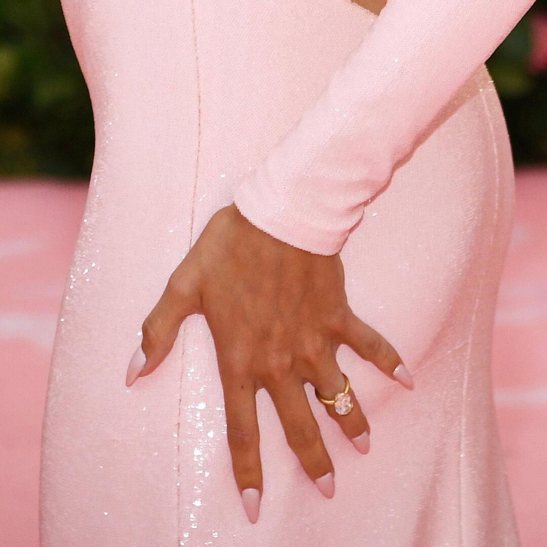 Close-up of Hailey Bieber's hand with matte pink ombre nails resting on her glittery pink dress Desktop