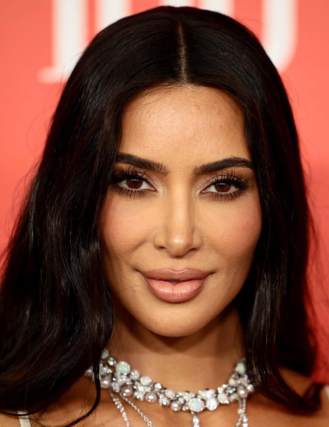 A close-up look of Kim Kardashian featuring a pearl and diamond necklace, along with her long black eyelashes accentuating her almond-shaped eyes Desktop