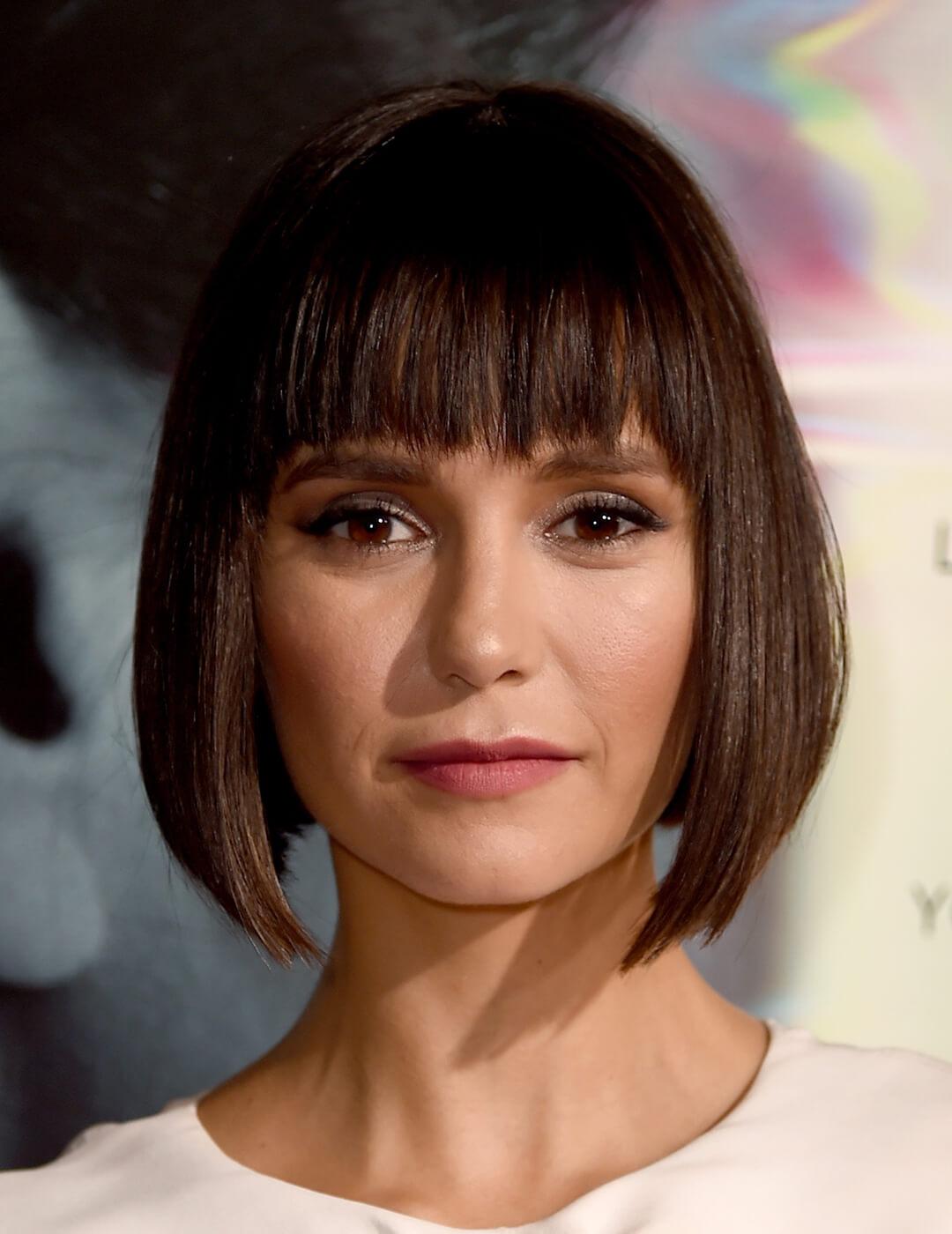 An image of Nina Dobrev relentlessly showcasing her brunette bob hair with full bangs on it Mobile