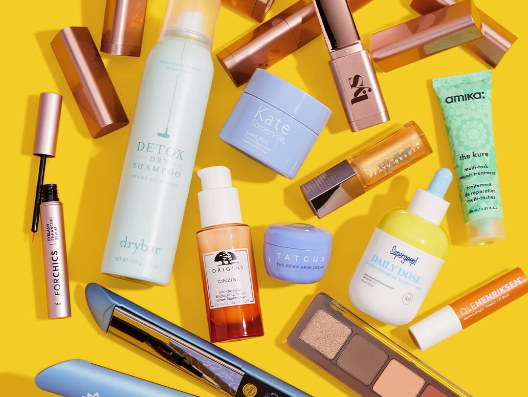 Beauty and makeup products from various brands scattered on yellow background Desktop