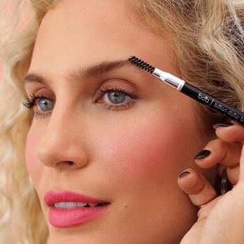 An image of a model brushing up her brows using the BILLION DOLLAR BROWS spoolie. Mobile