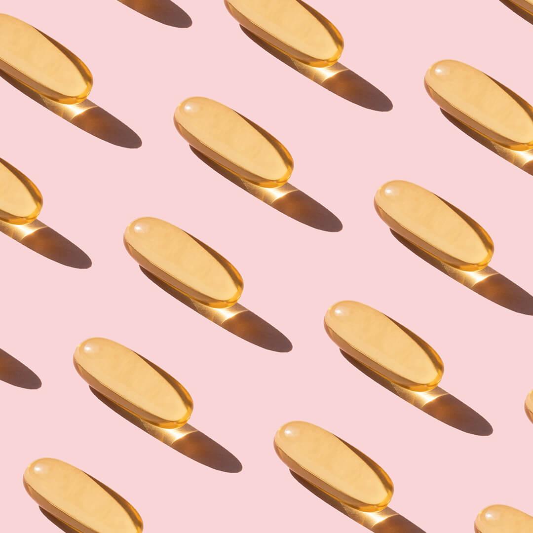 A photo of capsules diagonally lined up on a pink paper Desktop
