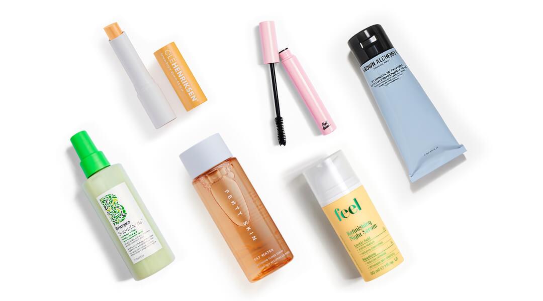 Skincare, makeup, and hair care products and tools from various brands scattered on white background Desktop