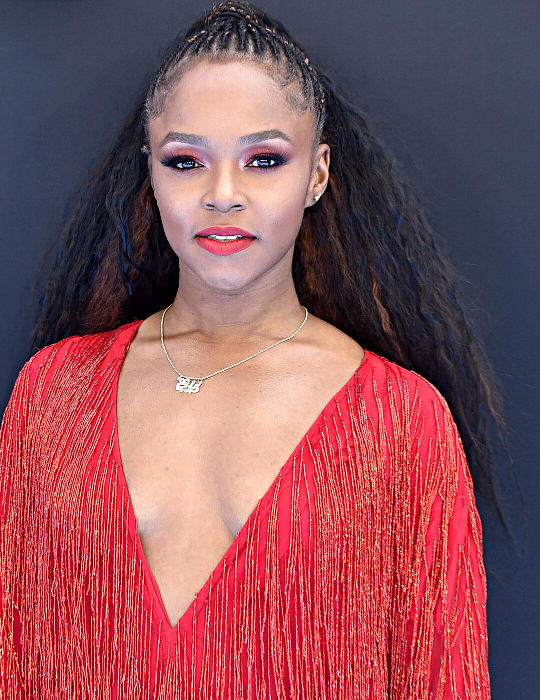 Gia Peppers rocking cornrows with half ponytail hairstyle, red monochromatic makeup look and red fringe dress Mobile