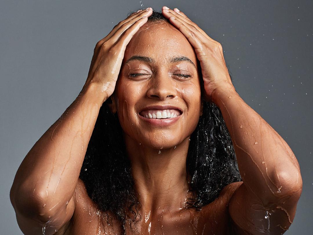 An image of a woman washing her hair against a grey background Desktop