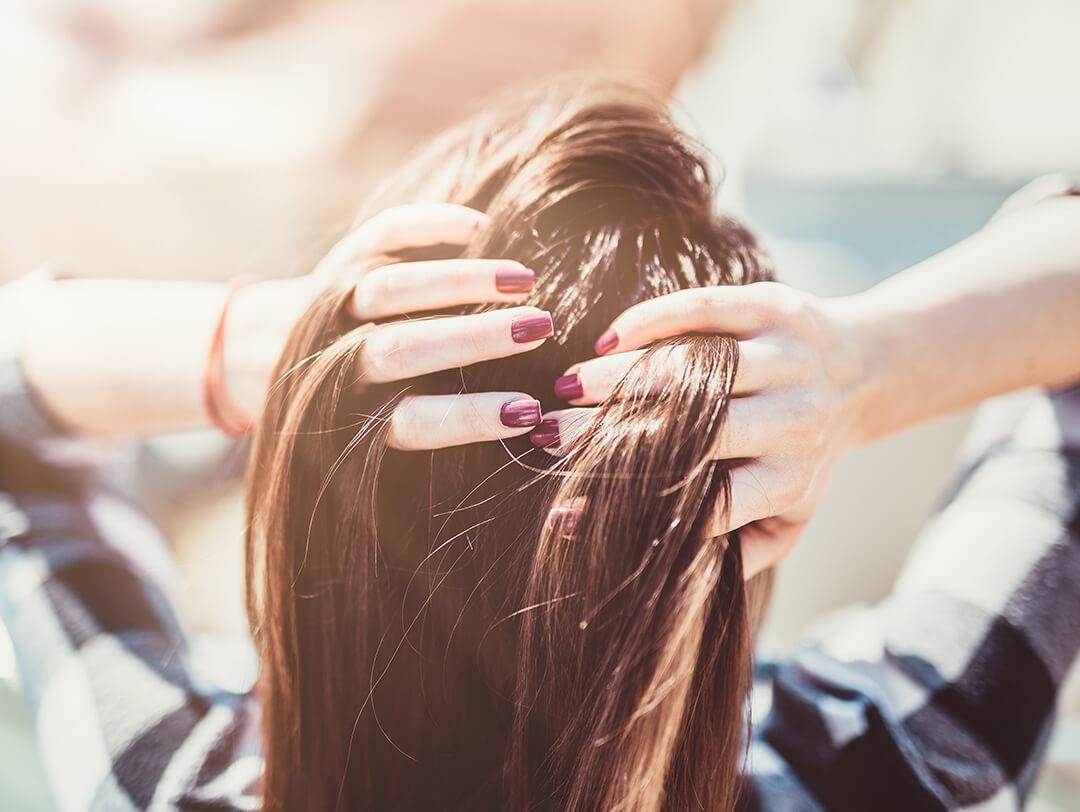 Image of a woman running her hands with purple mani through her dark hair Desktop