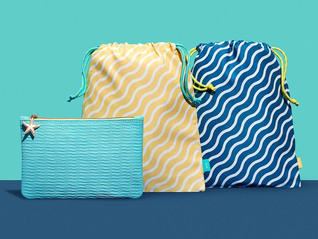 July 2022 IPSY Glam Bag and Glam Bag Plus bags on turquois and dark blue backgrounde Desktop