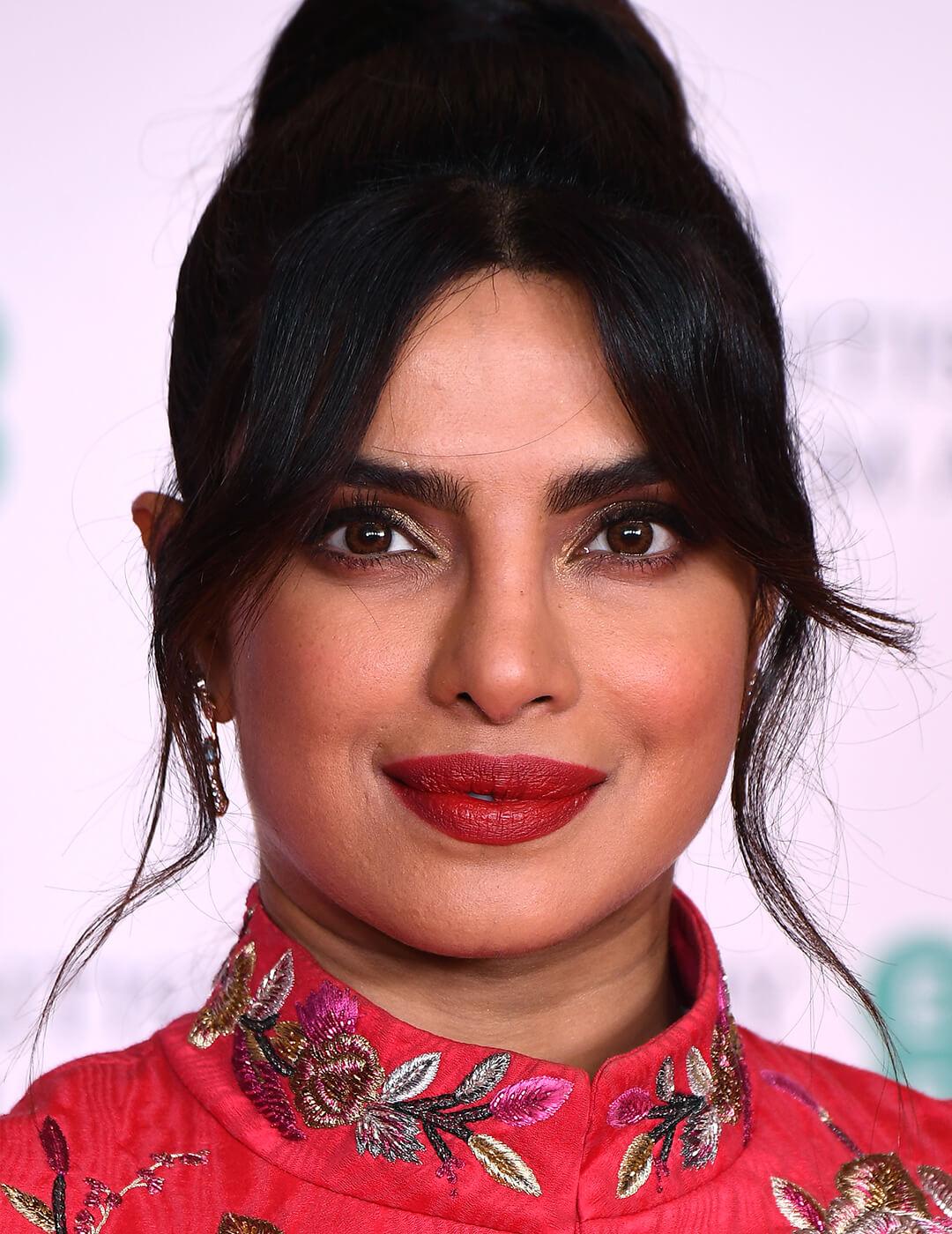 Priyanka Chopra Jonas rocking gold smoky eyeshadow makeup look, Chinese-themed dress, and updo hairstyle Mobile