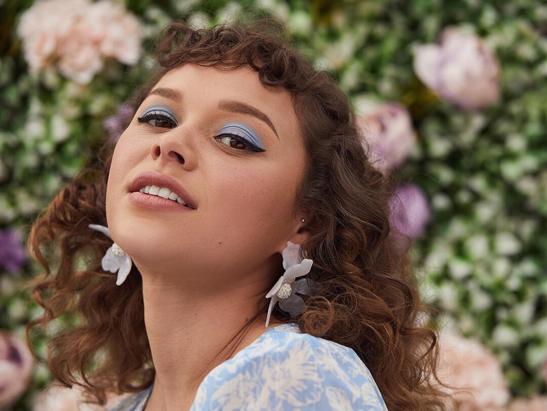 An image of a model in front of a wall of flowers. Desktop