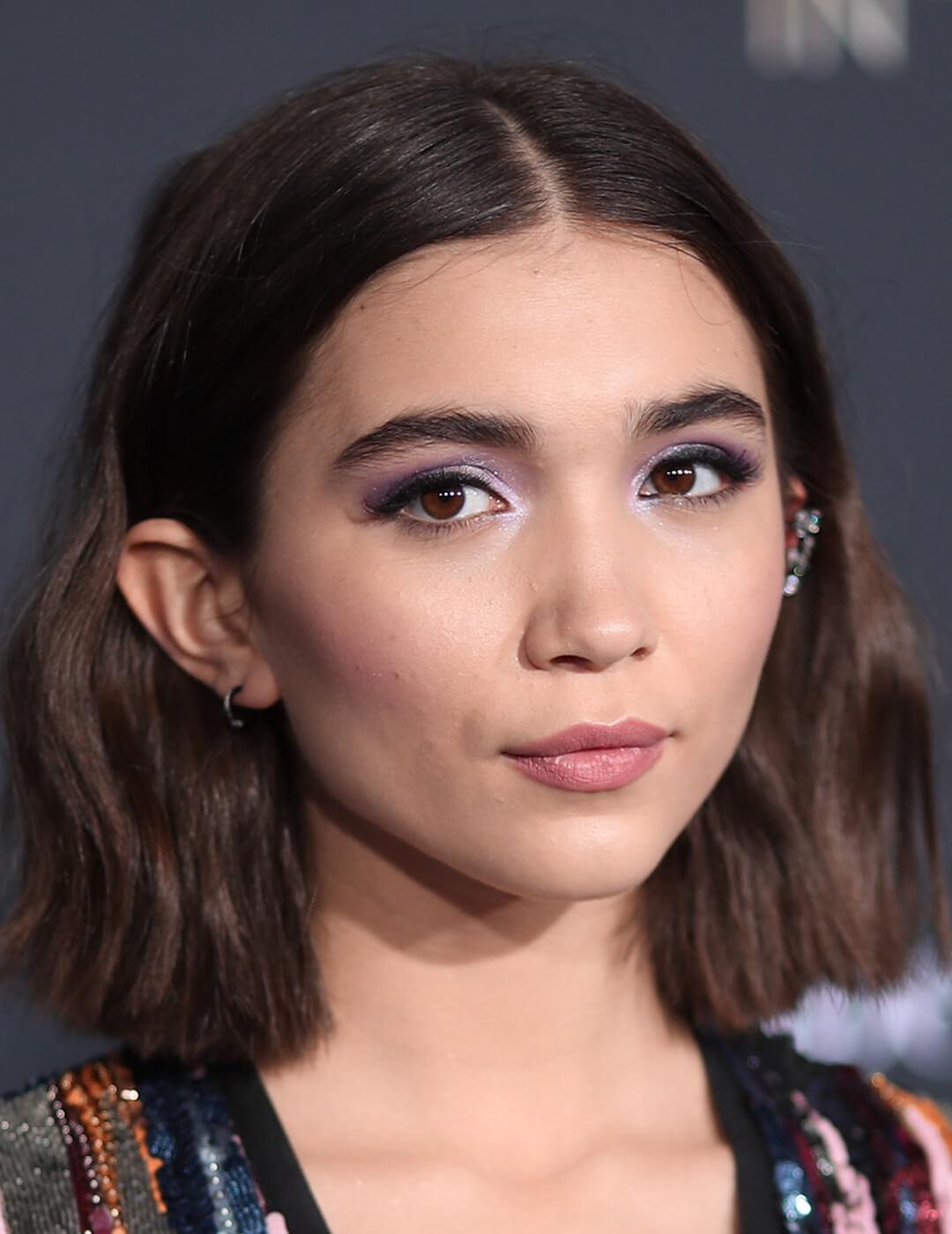 A photo of Rowan Blanchard with her hair tucked in both of her ears revealing her oval-shaped face on a black background Mobile