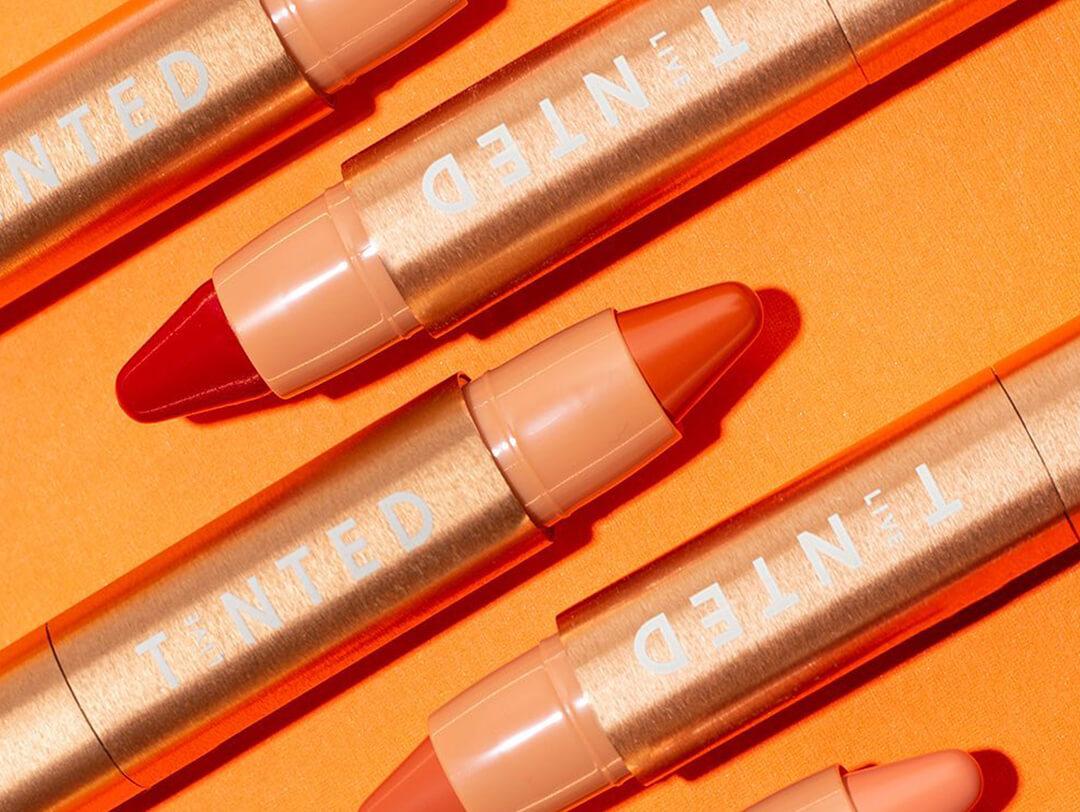 LIVE TINTED Huestick Color Correctors neatly arranged on orange background Desktop