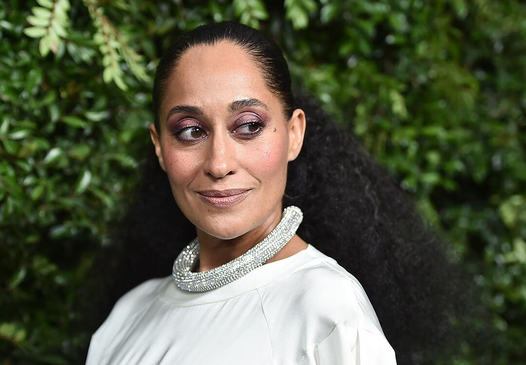 Tracee Ellis Ross in a silver dress rocking a dark purple eye makeup look, thick silver necklace, and a slicked back hairstyle Desktop
