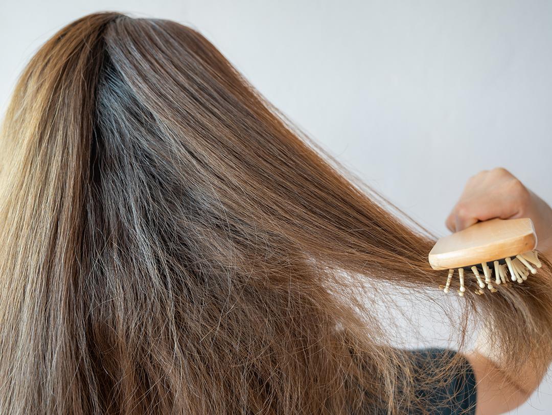 A photo of woman combing her dry hair with a wooden hairbrush Desktop