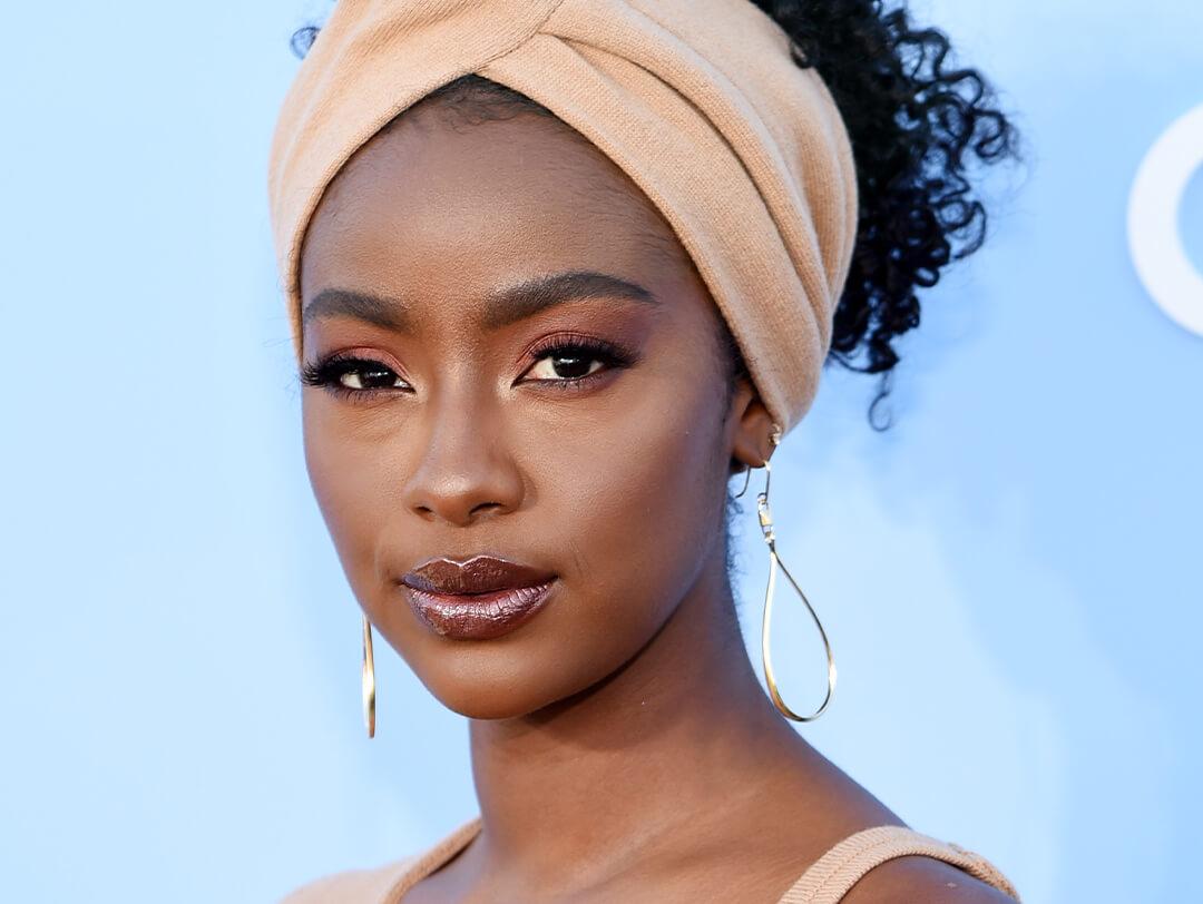 Justine Skye rocking a neutral makeup look, gold dangling earrings, and beige headwrap Desktop