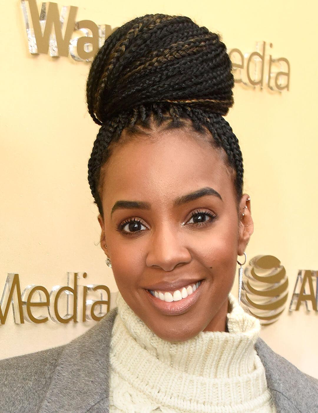 Kelly Rowland rocking her braided top bun hairstyle in an offwhite turtle neck sweater and grey coat Desktop