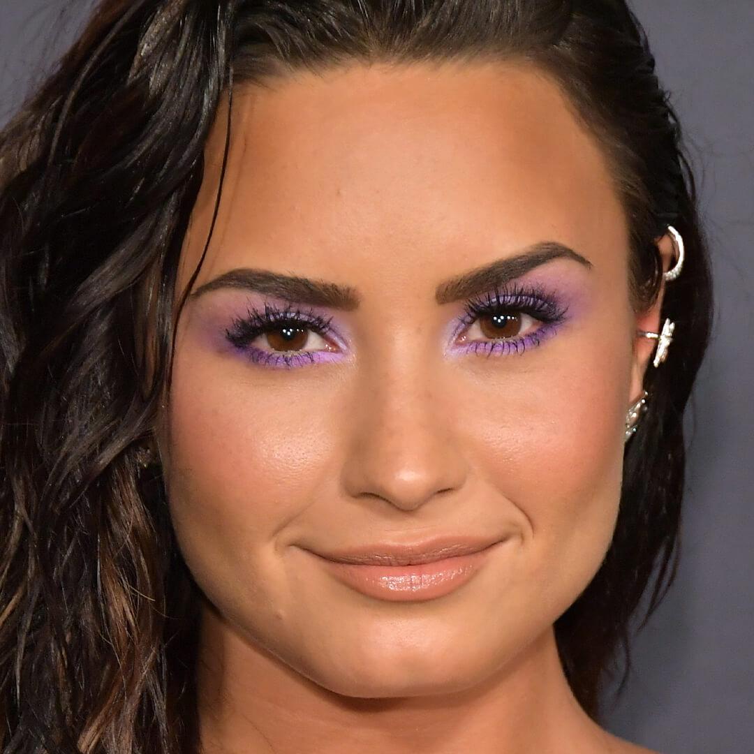 Close-up image of Demi Lovato rocking a purple eyeshadow look and bold lashes Desktop