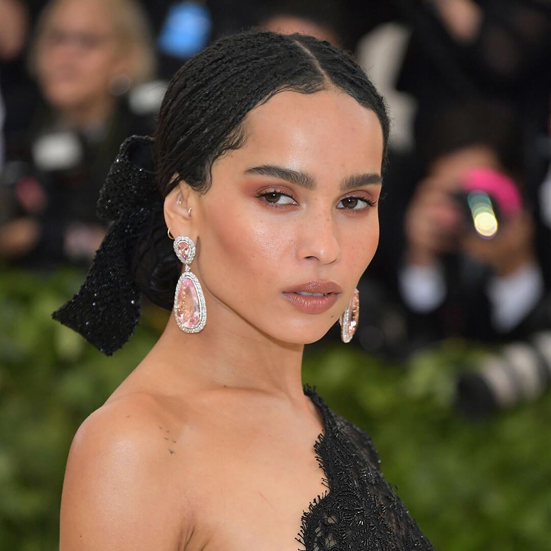 An image of Zoe Kravitz, with her Warm Neutral Monochromatic Makeup wearing a black mesh dress and her huge pink teardrop shape diamond earing Desktop