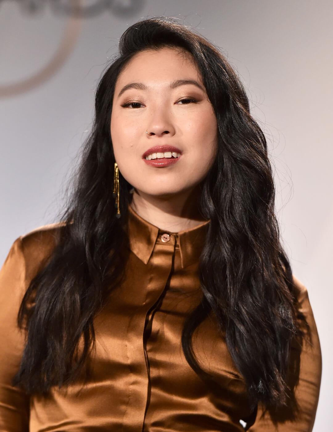 Awkwafina posing in a copper dress and beach waves hairstyle Desktop