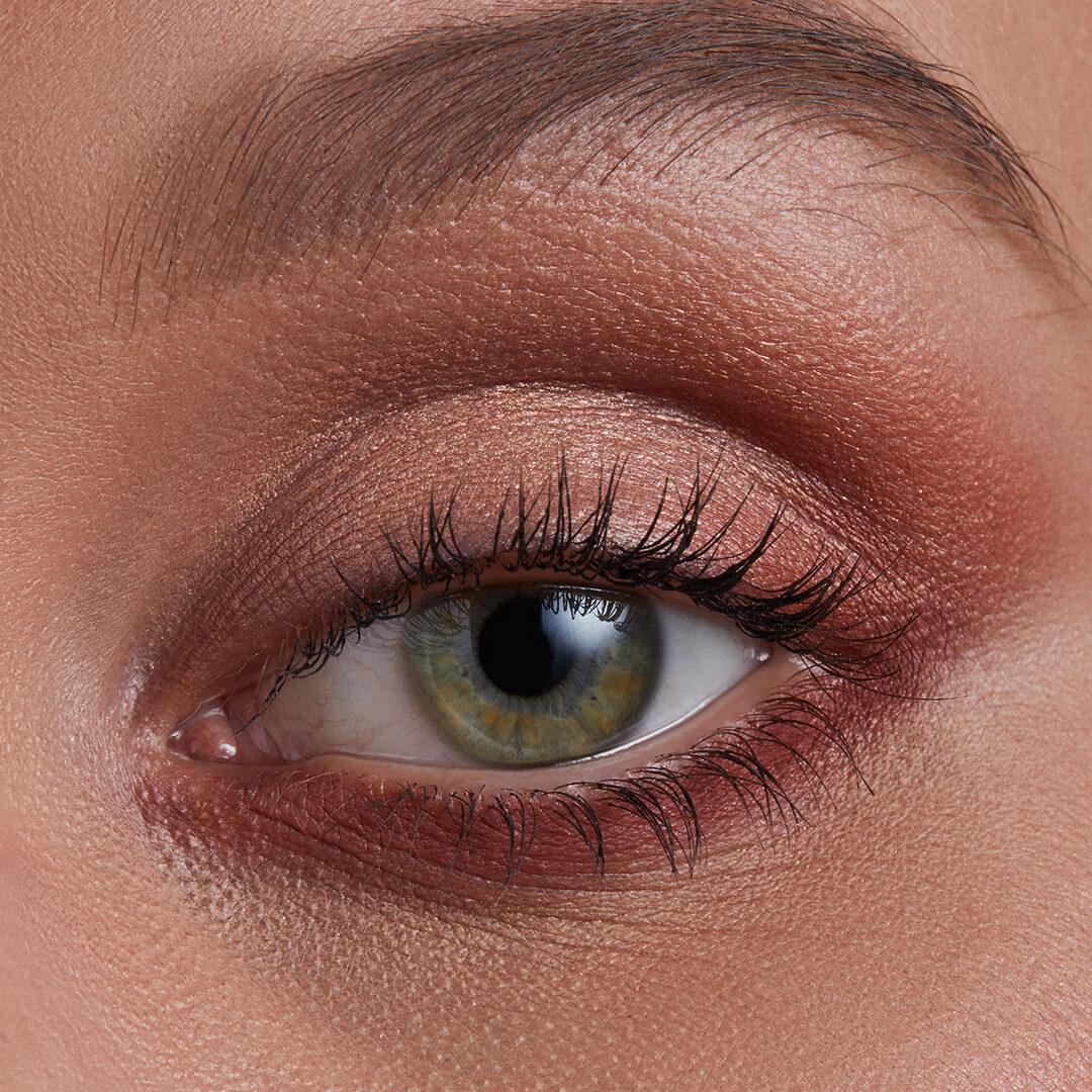 A close-up image of an eye wearing red eyeshadow. Mobile