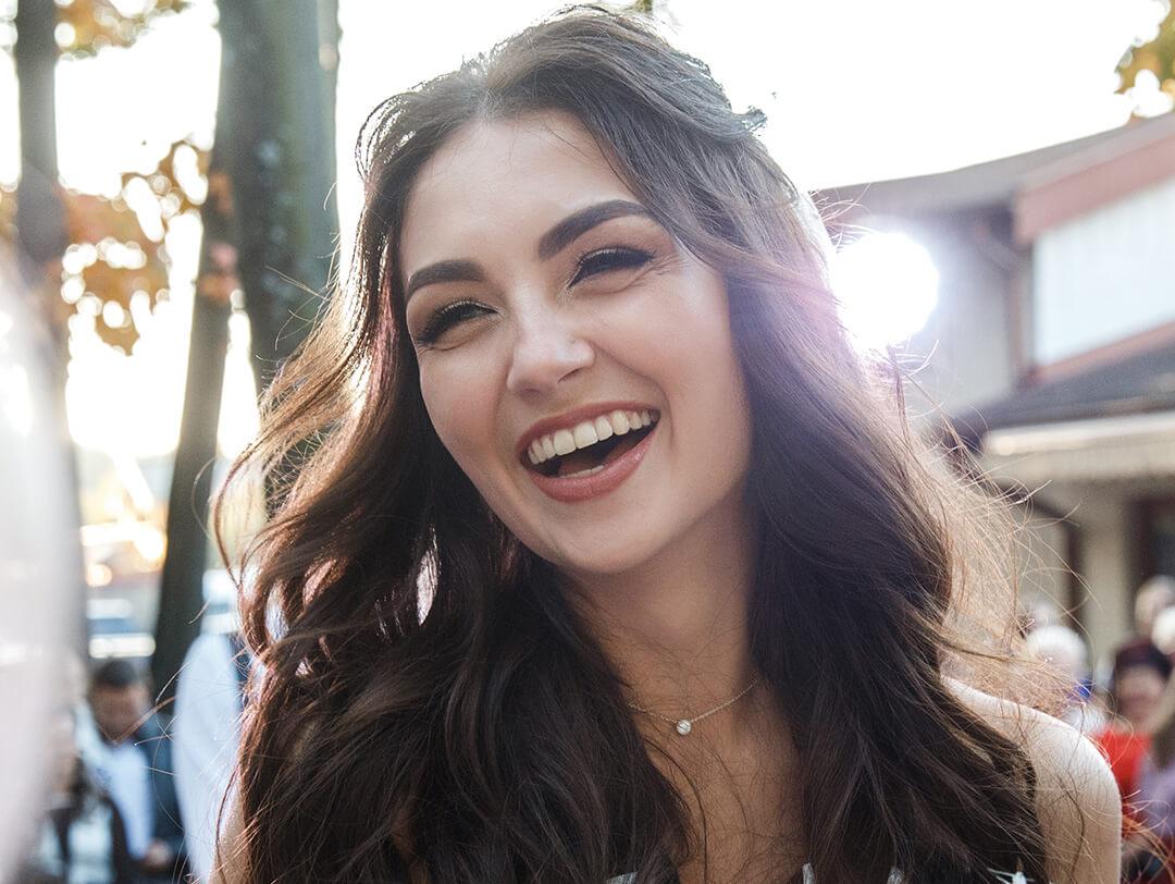 A photo of a bride with long dark hair smiles joyfully holding wedding bouquet Desktop
