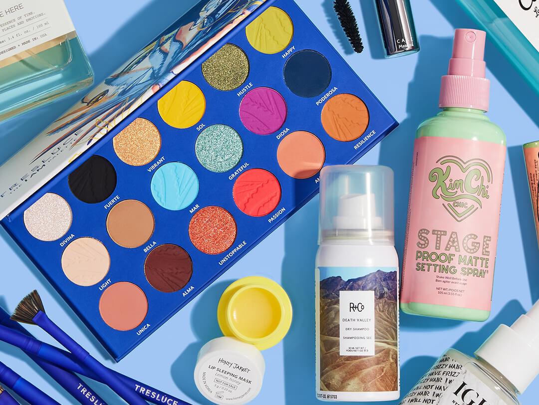 Beauty and makeup products from various brands scattered on light blue background Desktop
