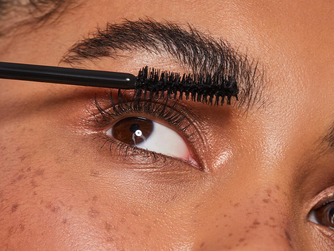 Close-up image of a woman applying mascara to her eyelashes Desktop