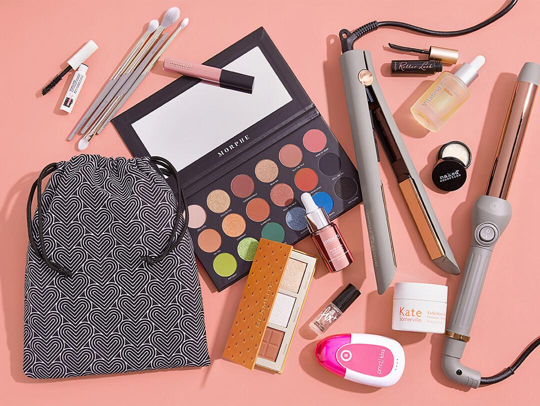 Makeup, skincare, and hair styling products and tools from various brands on peach background Desktop